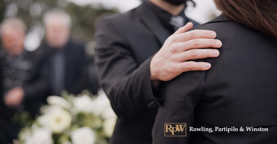 man trying to comfort a woman mourning at a funeral